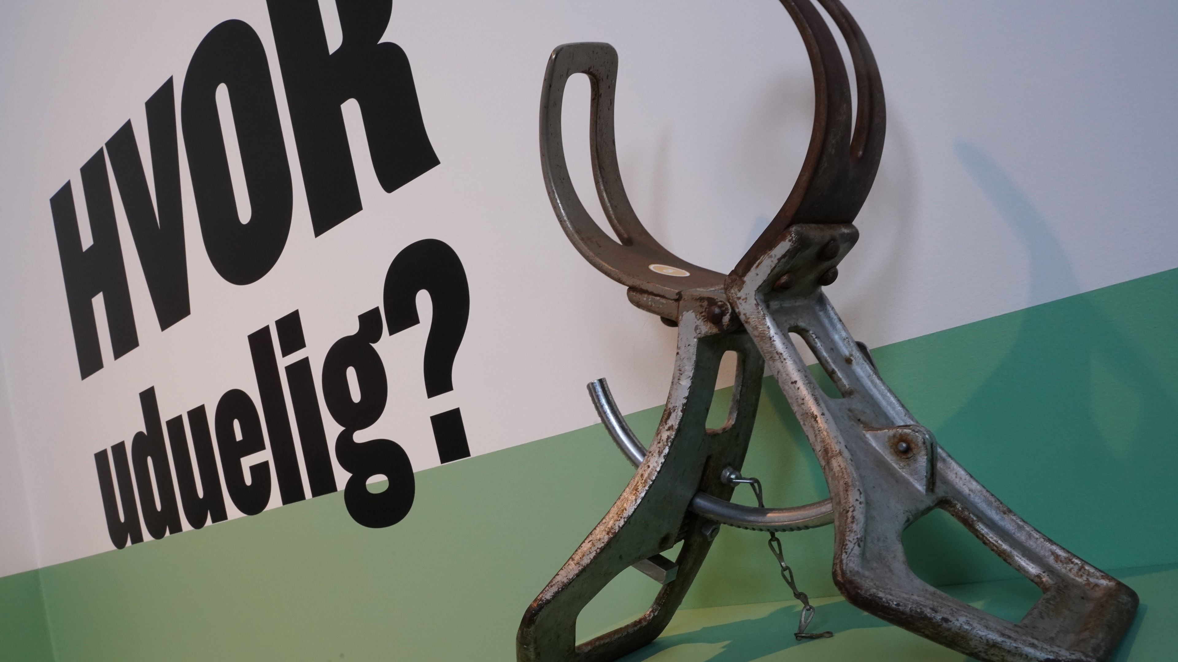 Foto af hovedmåler og skrift på væg: "Hvor uduelig?"